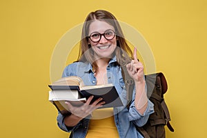 Attractive young female college student carrying a stack of books.