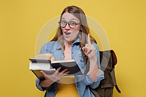 Attractive young female college student carrying a stack of books.