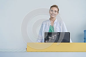 Attractive young female doctor leaning on the clinic reception desk, medical staff and healthcare concept.