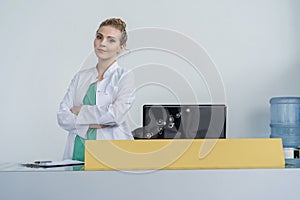 Attractive young female doctor leaning on the clinic reception desk, medical staff and healthcare concept.