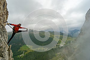 Attraente giovane una donna montagna alpinista sul Attraverso dolomiti pazzo allungamento posa 