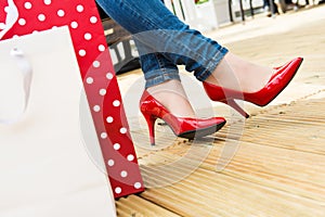 Attractive young female in red high heels enjoying a break after successful shopping