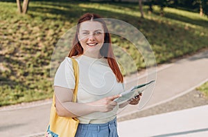 Attractive young female tourist is exploring new city. Happy redhead Woman with map in hands