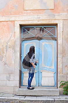 Attractive young female tourist opening door to a hostel