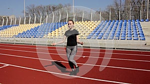 Attractive young fit active woman jumping with skipping rope working out warming up at big stadium on sunny spring day