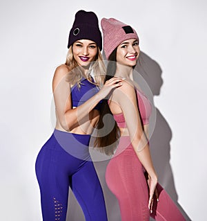 Attractive, young and fit women with long hair wearing sports clothing and knitted hats over a white background