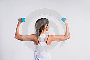 Attractive young fitness woman holding dumbells. Studio shot.