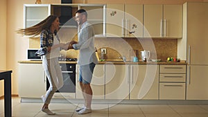 Attractive young funny couple have fun dancing while cooking in the kitchen at home