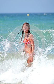 Attractive young girl being splashed by cold wave in the se