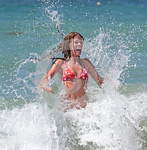 Attractive young girl being splashed by cold wave in the se