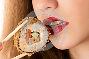 Attractive young girl eating sushi roll, closeup mouth