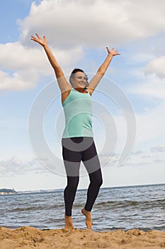 Attractive young girl jumping on a beach in the summer