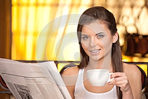 Attractive young girl reading newspaper.