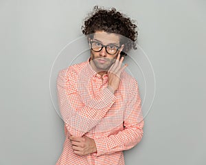 attractive young guy with glasses folding arms and touching jawline