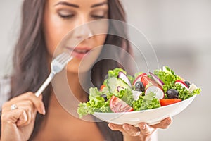 Attractive young and happy woman eating vegetable salad