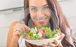 Attractive young and happy woman eating vegetable salad