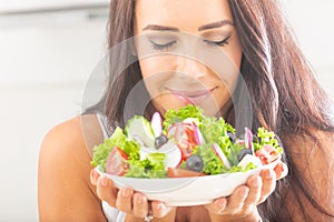 Attractive young and happy woman eating vegetable salad