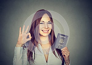 Attractive young happy woman with USA passport giving ok sign