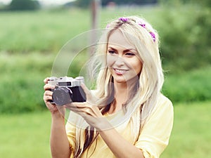 Attractive, young hippie girl taking pictures outdoors at summer. Holiday, vacation, hobby concept.