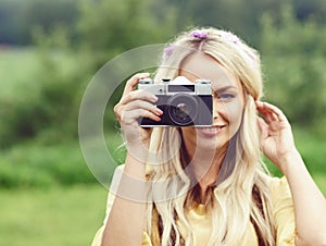 Attractive, young hippie girl taking pictures outdoors at summer. Holiday, vacation, hobby concept.