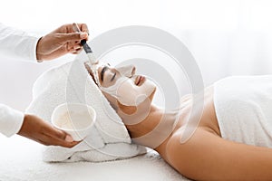 Attractive young indian woman receiving skin treatment at spa center