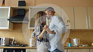 Attractive young funny couple have fun dancing while cooking in the kitchen at home