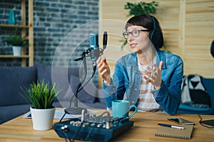 Attractive young lady speaking in microphone gesturing in studio