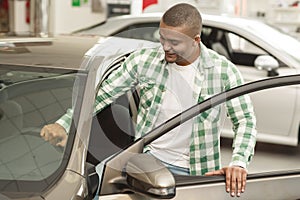 Handsome African man choosing new car at dealership