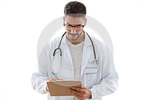Attractive young male doctor with stethoscope over neck taking notes in clipboard isolated on white background.