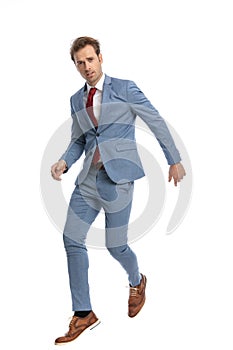 Attractive young man in blue suit jumping in the air