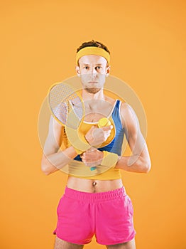 Attractive young man in casual costume holding tennis racket and ball.