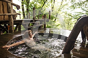 Attractive young man with curly, fair hair is relaxing in the cold tub