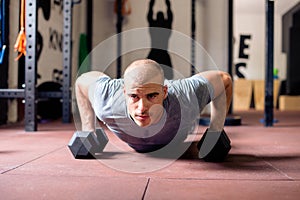 Attractive young man doing push-ups with weights