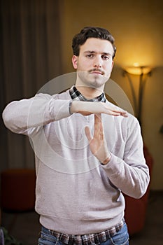 Attractive young man doing time-out sign