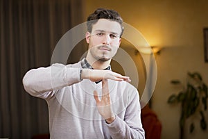 Attractive young man doing time-out sign