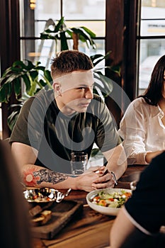 Attractive young man drinking draft beer while having fun in pub or bar with friends and laughing