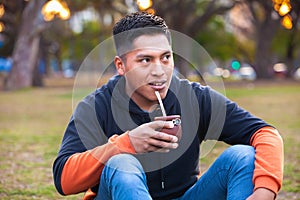 Attractive young man drinking yerba mate, herbal tea