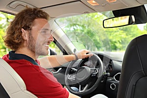 Attractive young man driving his car, view from backseat