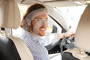 Attractive young man driving his car, view from backseat