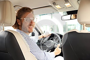 Attractive young man driving his luxury car, view from