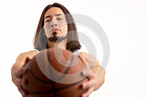 Attractive young man holds basketball ball in front of him, focus on the man studio shot isolated white background copy