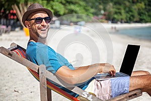 Attractive young man with laptop working on the beach. Freedom,