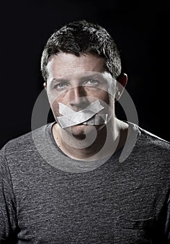 Attractive young man with mouth sealed on duct tape to prevent him from speaking