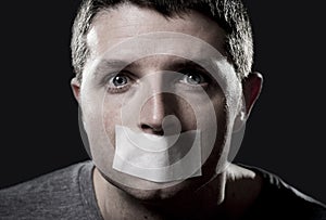 Attractive young man with mouth sealed on duct tape to prevent him from speaking