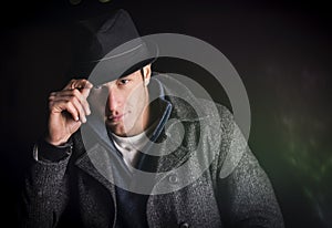 Attractive young man at night, wearing winter coat and fedora hat