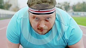 Attractive young man obese outside in the stadium at the starting line getting ready to start running hard. Shot on ARRI