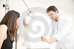 Attractive young man ophthalmologist doing eye examination to woman at clinic