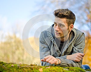 Attractive young man outdoors in nature lying on moss