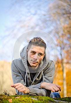 Attractive young man outdoors in nature lying on moss