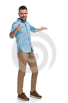 Attractive young man pointing finger and presenting to side